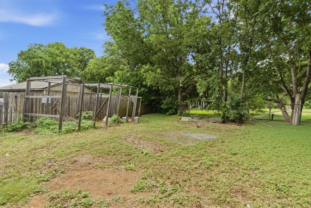 302 Tower Road Rio Vista, TX 76093 - Photo 7 of 29 Expansive outdoor space featuring a wooden fence, multiple mature trees, a clear blue sky, and a garden structure