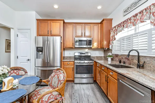 a kitchen with stainless steel appliances granite countertop a refrigerator sink and wooden cabinets