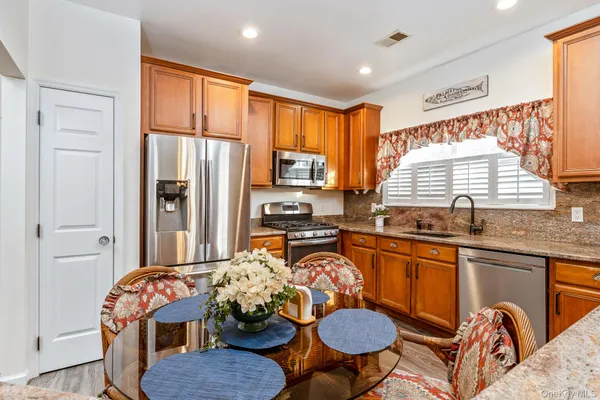 a kitchen with stainless steel appliances granite countertop a stove top oven a sink a dining table and chairs