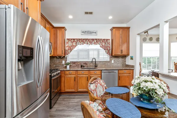 a kitchen with granite countertop lots of counter top space wooden floor and stainless steel appliances