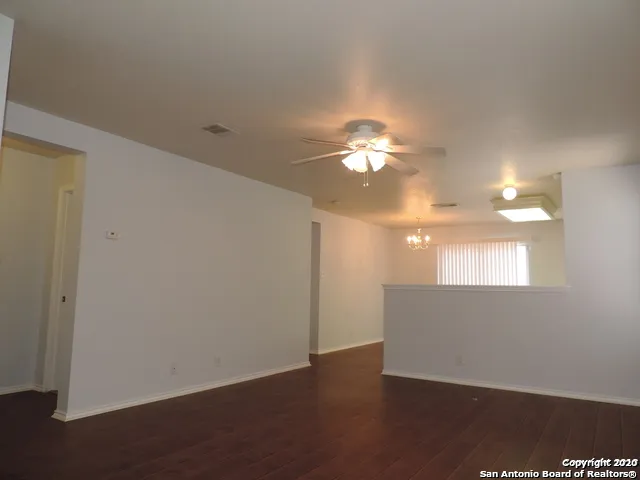 an empty room with wooden floor and chandelier fan