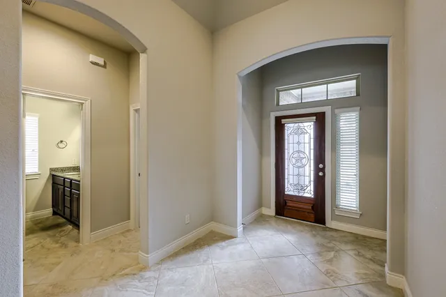 an empty room with a chandelier fan and windows