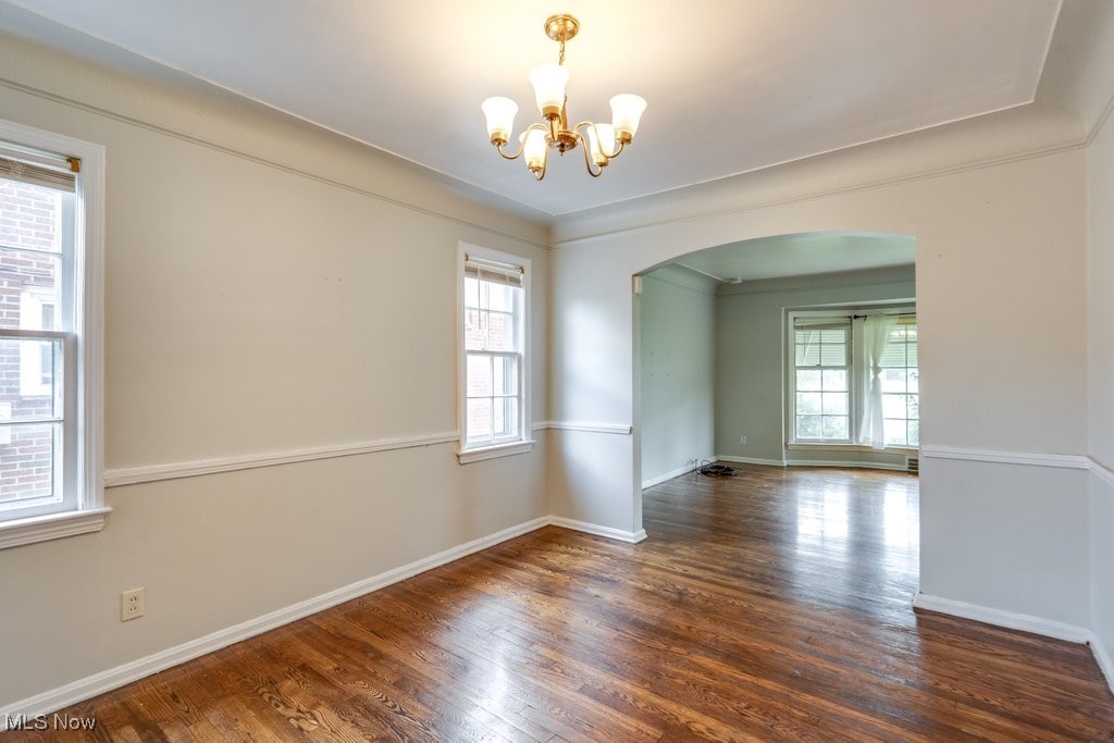 13677 Cedar Road Cleveland, OH 44118 - Photo 17 of 50 Spare room featuring arched walkways, dark wood-style floors, a chandelier, and crown molding