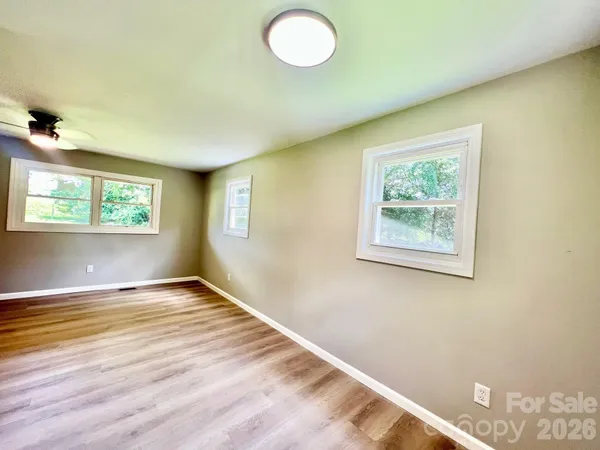 a view of an empty room with a window and wooden floor
