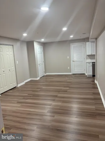 a view of a big room with wooden floor and a kitchen