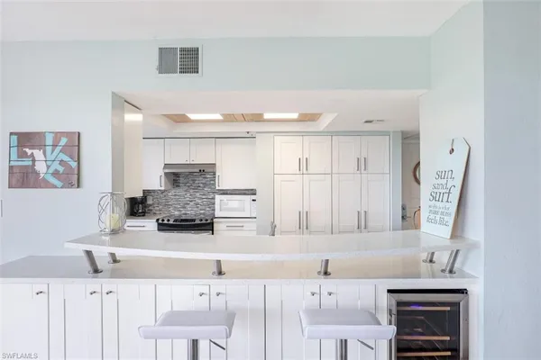 a kitchen with stainless steel appliances kitchen island granite countertop a sink and a white cabinets