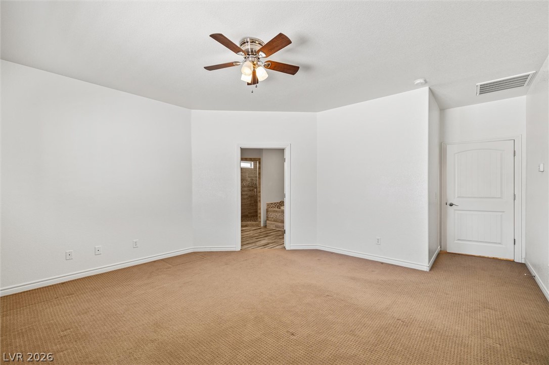 6720 Stubblefield Drive Pahrump, NV 89061 - Photo 27 of 51 A well-lit primary bedroom offers carpeting and a convenient en-suite bathroom access.