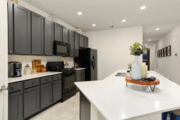 a kitchen with kitchen island granite countertop wooden cabinets a stove a sink and a refrigerator