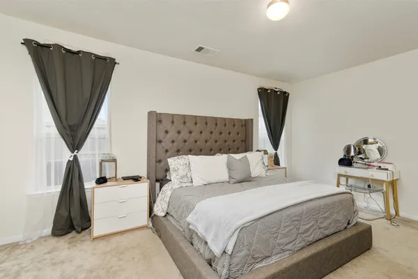 a bedroom with a bed a mirror and a flat tv screen on a dresser