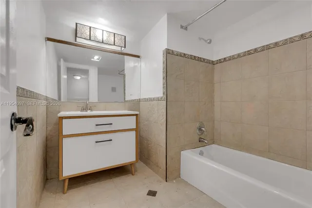 a bathroom with a double vanity sink a mirror a bathtub and shower