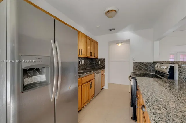 a kitchen with stainless steel appliances granite countertop a refrigerator a stove and a sink with wooden floor