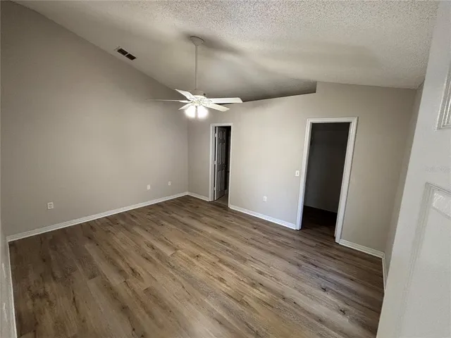 an empty room with wooden floor and a ceiling fan