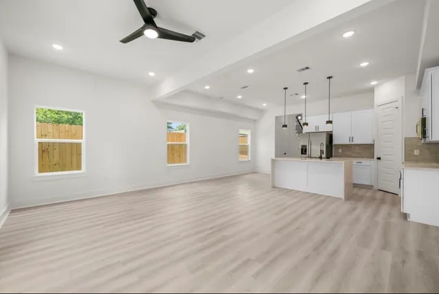 a view of kitchen with kitchen island stainless steel appliances wooden floor cabinets and a window