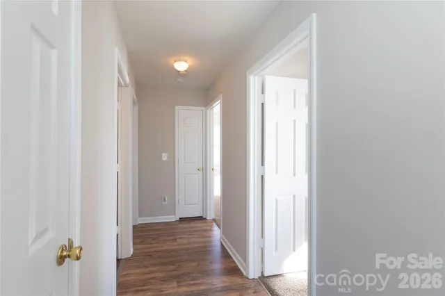 a view of a hallway with wooden floor and a bathroom