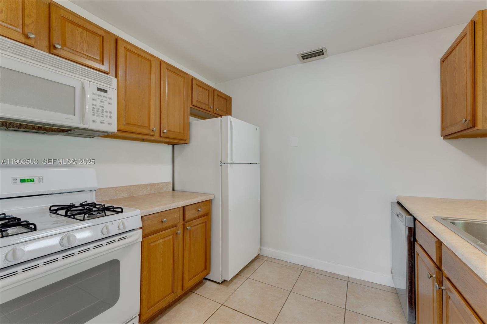 8670 Southwest 27th Lane Miami, FL 33155 - Photo 16 of 31 a kitchen with granite countertop a sink stove and refrigerator