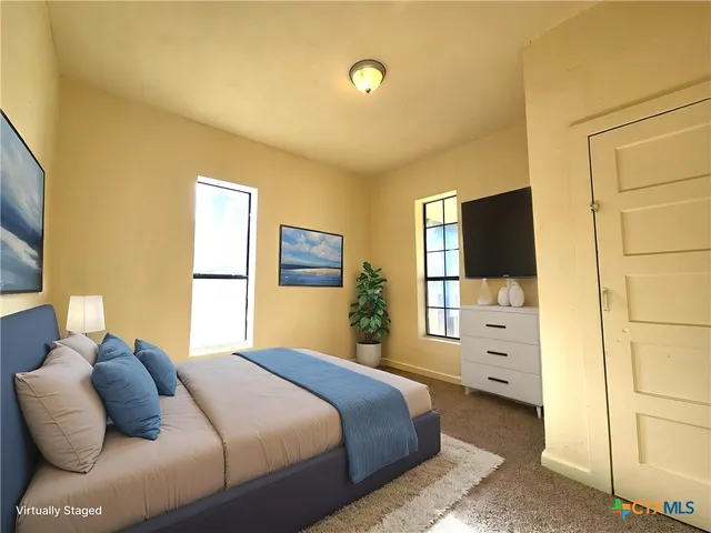 a bedroom with a bed and a flat tv screen on dresser