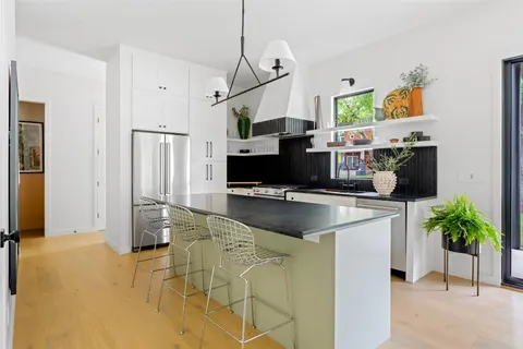 a kitchen with stainless steel appliances kitchen island granite countertop a refrigerator a stove and a sink