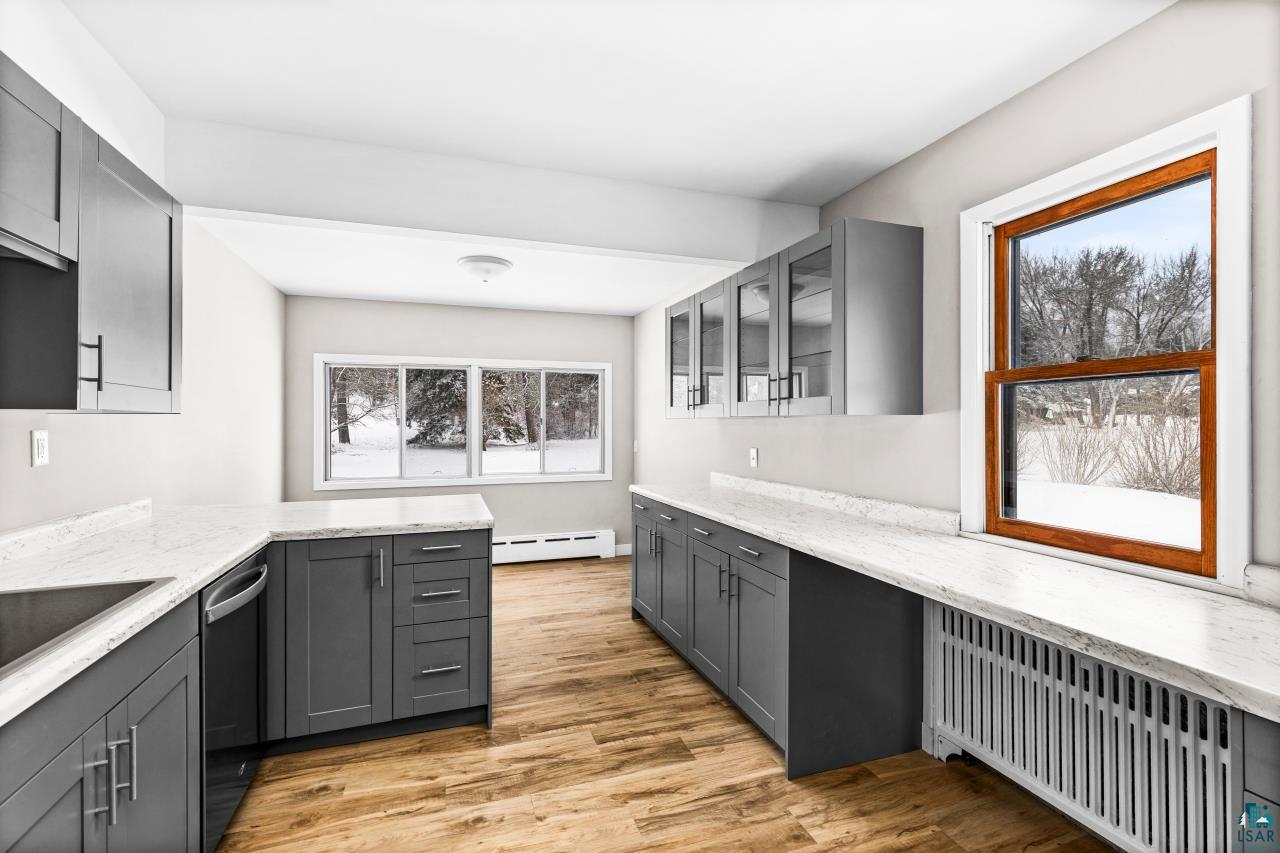 3754 Carlton Street Barnum, MN 55707 - Photo 11 of 52 Kitchen with gray cabinetry, radiator, glass fronted cabinets, light wood-style flooring, and light stone counters