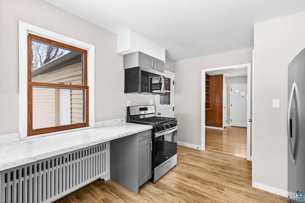 3754 Carlton Street Barnum, MN 55707 - Photo 15 of 52 Kitchen with radiator heating unit, stainless steel appliances, gray cabinetry, and light wood-type flooring