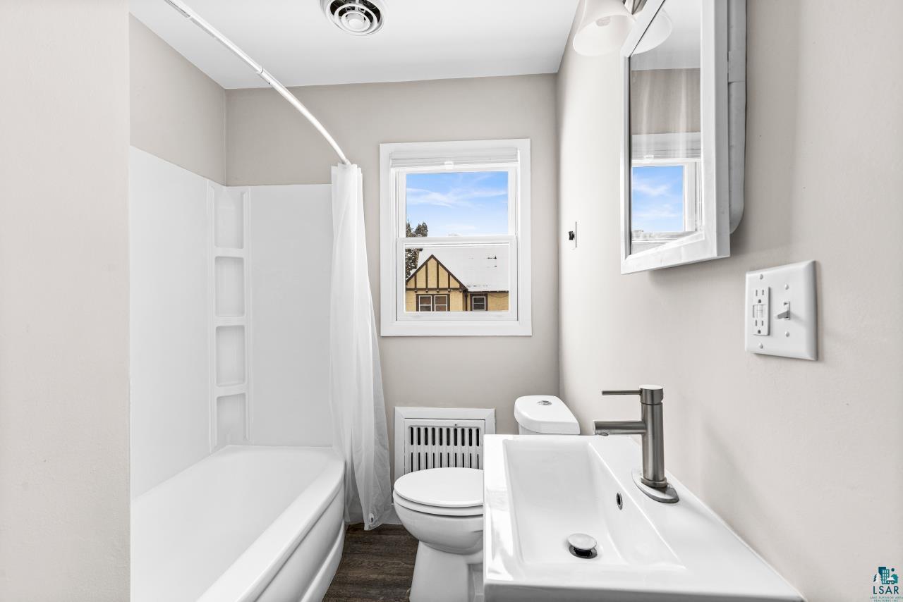 3754 Carlton Street Barnum, MN 55707 - Photo 21 of 52 Bathroom featuring vanity, dark wood-style floors, and shower / tub combo with curtain