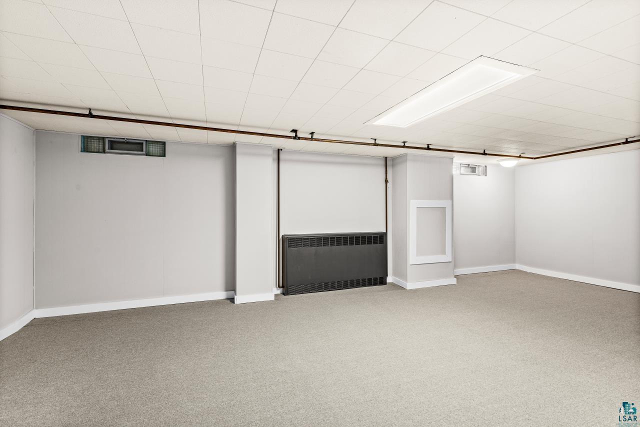 3754 Carlton Street Barnum, MN 55707 - Photo 29 of 52 Finished basement with radiator heating unit and carpet flooring