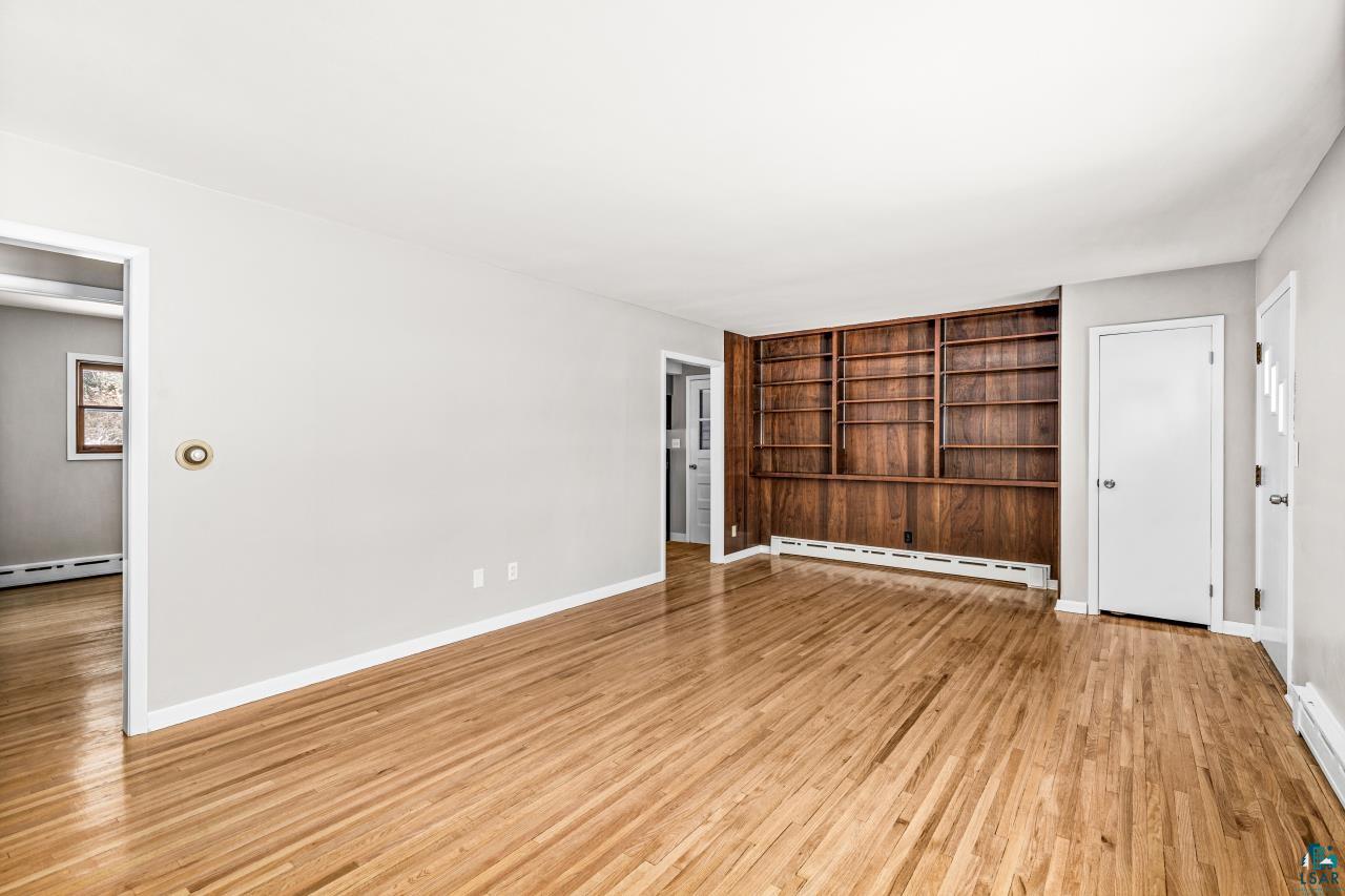 3754 Carlton Street Barnum, MN 55707 - Photo 36 of 52 Unfurnished living room with a baseboard radiator, light wood-type flooring, a baseboard heating unit, and built in features