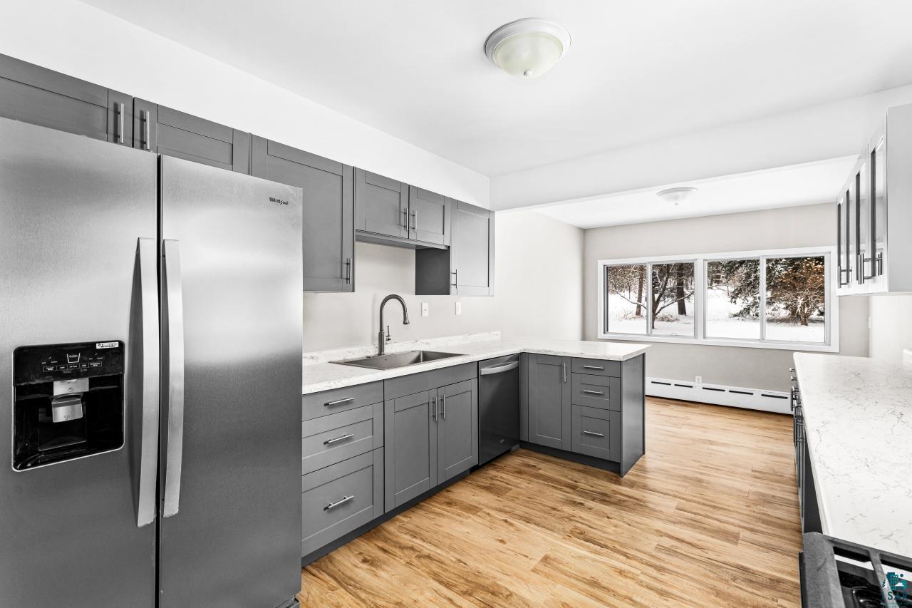 3754 Carlton Street Barnum, MN 55707 - Photo 8 of 52 Kitchen with stainless steel appliances, gray cabinetry, light stone countertops, light wood-style flooring, and a peninsula