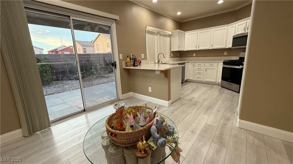 7062 Russell Ranch Avenue Las Vegas, NV 89113 - Photo 10 of 32 Kitchen with light wood-style flooring, a peninsula, a sink, and stainless steel appliances