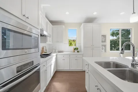 a kitchen with white cabinets appliances and a window