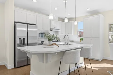 a kitchen with kitchen island stainless steel appliances a table chairs sink and cabinets