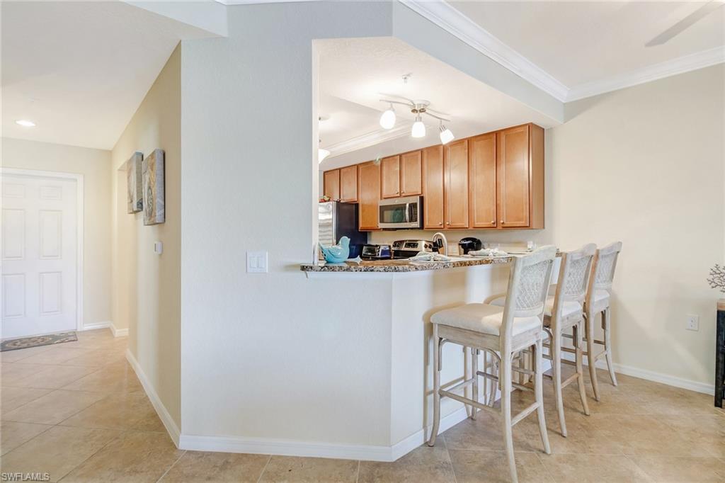 9514 Avellino Way, Unit 2116 Naples, FL 34113 - Photo 9 of 30 a kitchen with kitchen island granite countertop a stove cabinets dining table and chairs