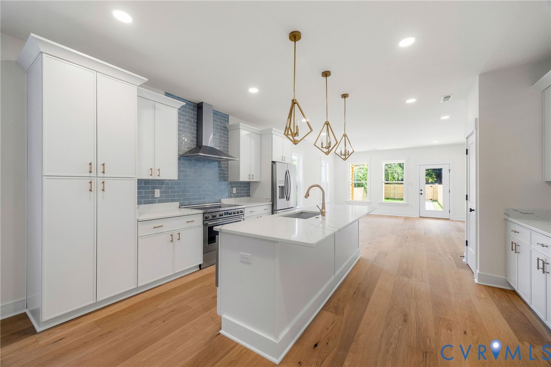3423 Stuart Avenue Richmond, VA 23221 - Photo 11 of 34 a large kitchen with kitchen island a stove a sink a refrigerator and white cabinets with wooden floor