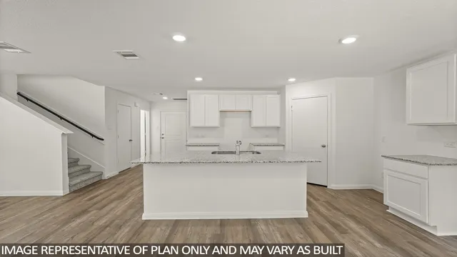 a large white kitchen with kitchen island a sink dishwasher stove with wooden floor and cabinets