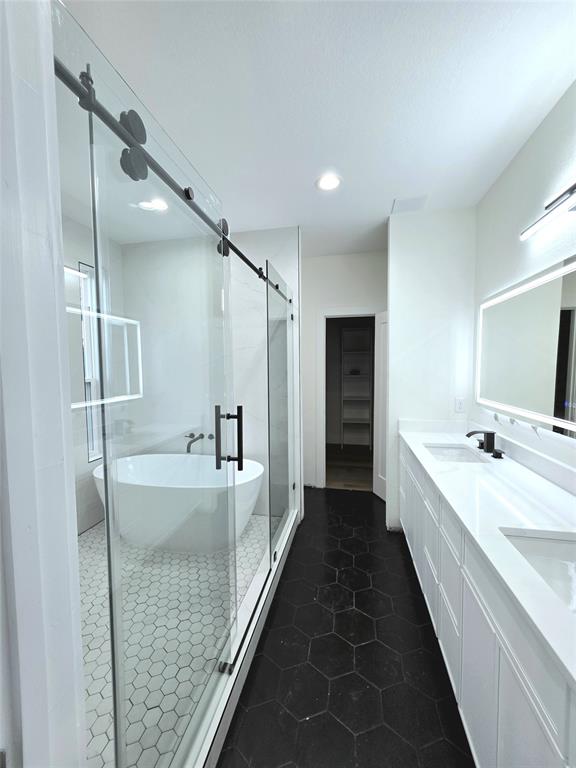 3905 Blue Ridge Boulevard Dallas, TX 75233 - Photo 8 of 9 Contemporary bathroom featuring a freestanding tub within a glass-enclosed shower, dual vanities with integrated sinks, and black hexagonal floor tiling