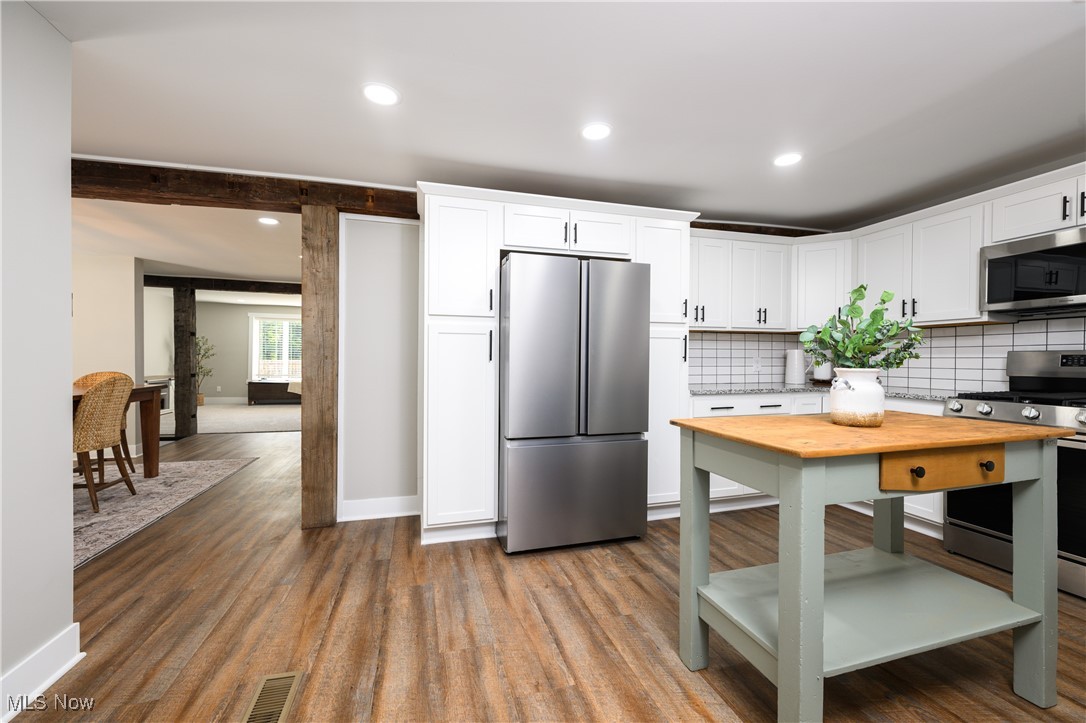 3029 Werner Church Road Northeast Canton, OH 44721 - Photo 11 of 33 Kitchen with hardwood / wood-style floors, appliances with stainless steel finishes, decorative backsplash, and white cabinetry