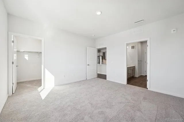 a view of an empty room with closet and bathroom
