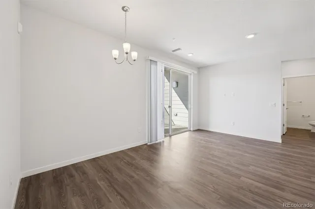 a view of an empty room with wooden floor and windows