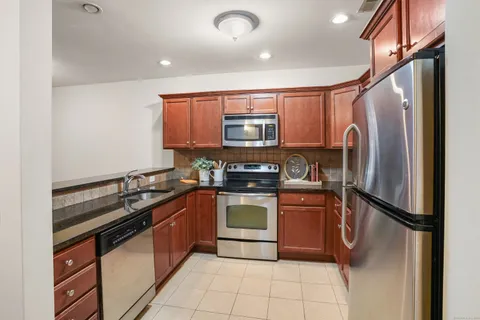 a kitchen with stainless steel appliances granite countertop a stove top oven a sink and a refrigerator