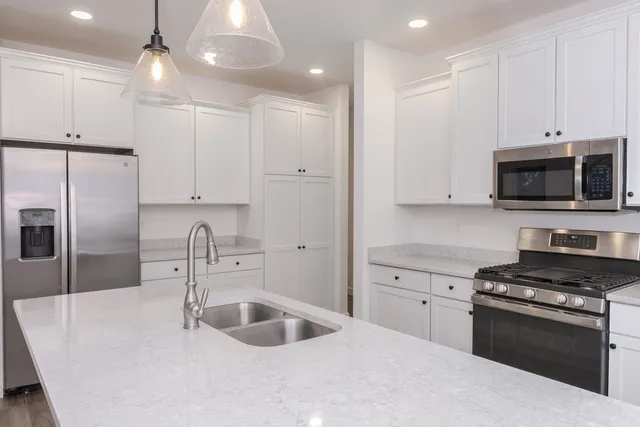 a kitchen with stainless steel appliances a sink a stove a microwave and island