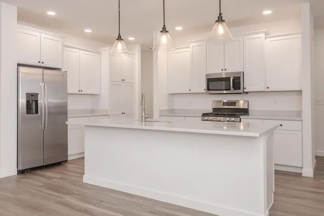 a kitchen with kitchen island white cabinets and stainless steel appliances