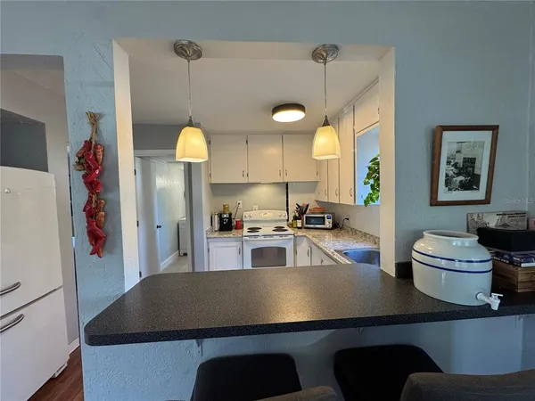 a kitchen with stainless steel appliances a sink a stove a refrigerator a dining table and chairs with wooden floor