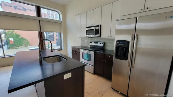a kitchen with stainless steel appliances a refrigerator a sink a stove and cabinets