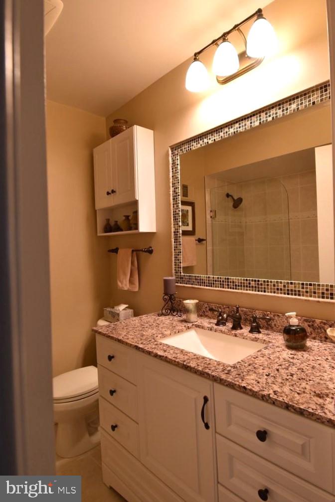 8244 Carrleigh Parkway Springfield, VA 22152 - Photo 20 of 25 a bathroom with a granite countertop sink a toilet and mirror