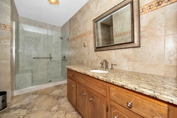a bathroom with a granite countertop sink a mirror and shower