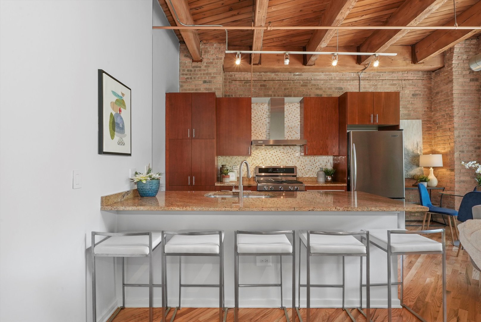 1040 West Adams Street, Unit 213 Chicago, IL 60607 - Photo 2 of 30 a kitchen with kitchen island granite countertop a stove a sink and a refrigerator