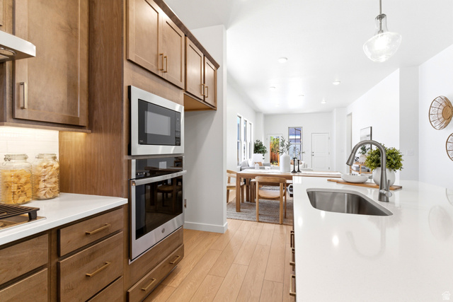 7243 West Terraine Road West Jordan, UT 84081 - Photo 8 of 31 Contemporary kitchen featuring wood-finish cabinetry, stainless steel appliances, a built-in oven and microwave, and light-toned countertops with an undermount sink