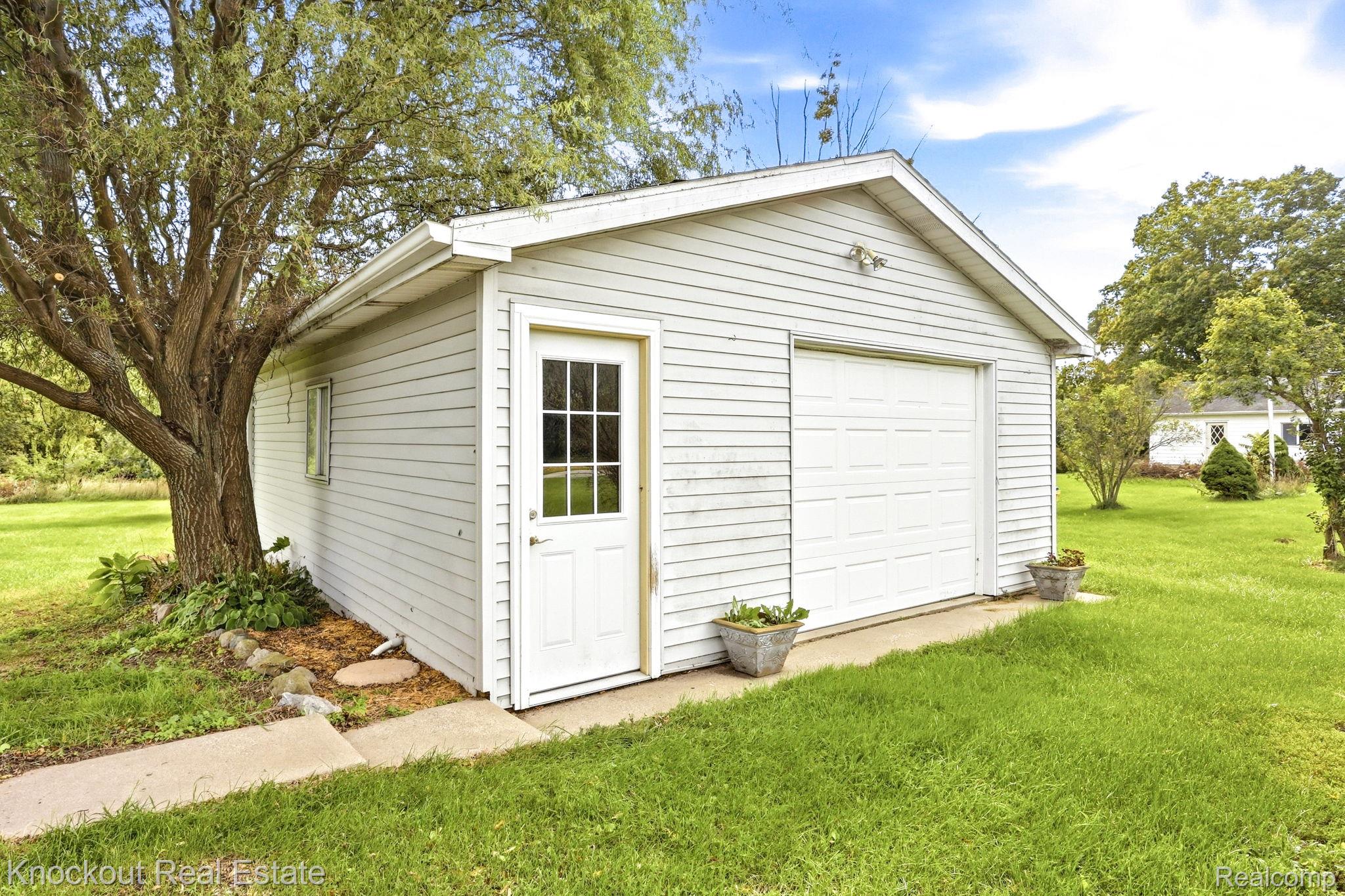 8771 Van Cleve Road Vassar, MI 48768 - Photo 31 of 44 Detached garage with horizontal siding, a single panel garage door, and a separate entry door with grid glass