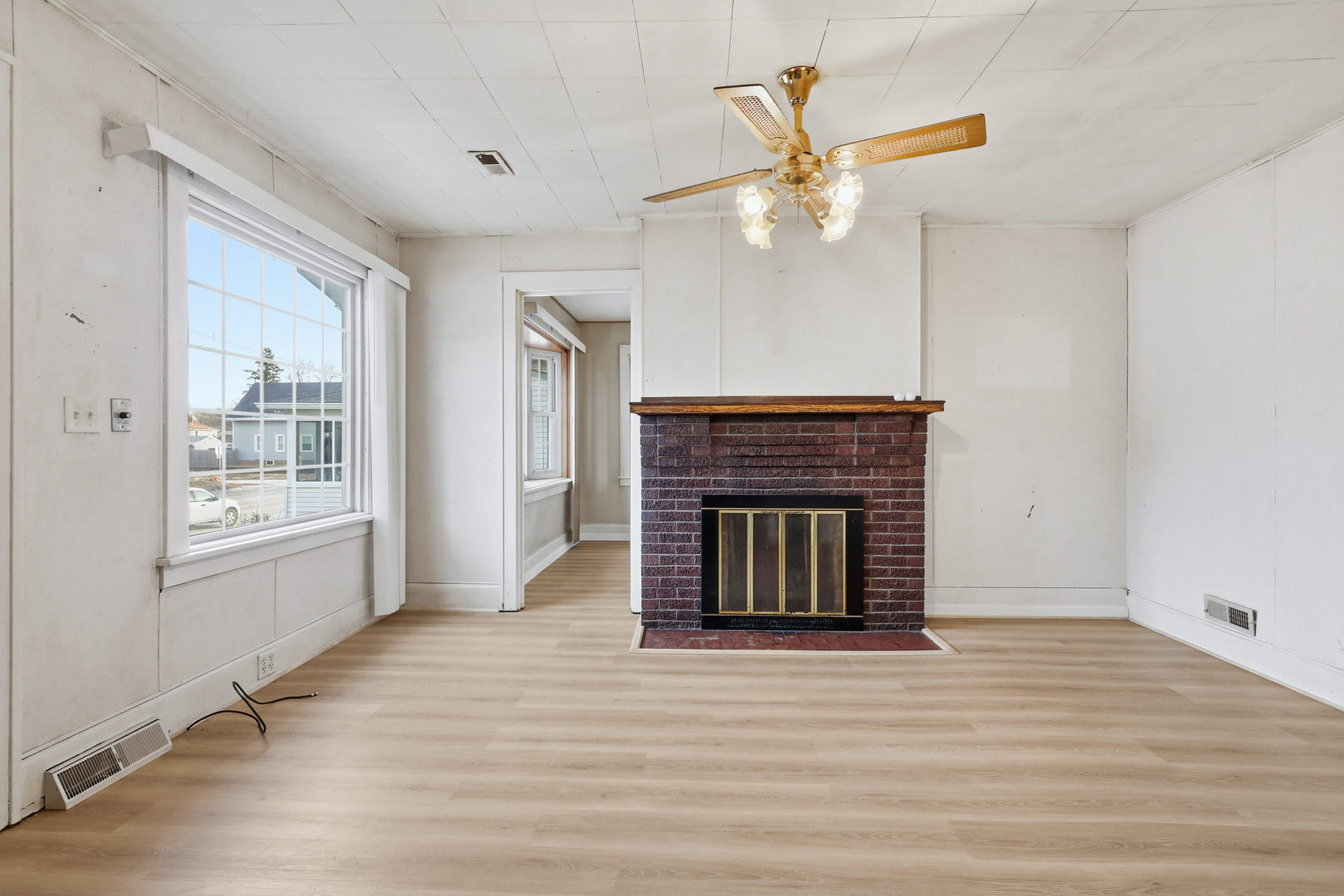 2748 12th Avenue Moline, IL 61265 - Photo 11 of 35 an empty room with wooden floor a ceiling fan a fireplace and windows