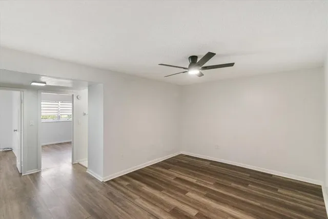 a view of empty room with wooden floor and ceiling fan