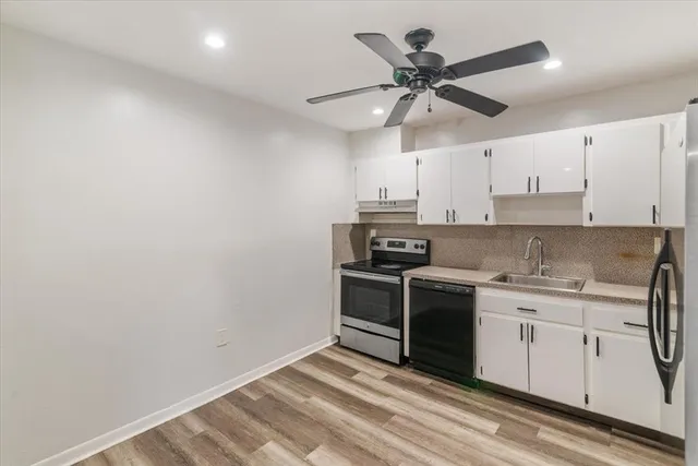 a kitchen with stainless steel appliances a stove a sink and white cabinets